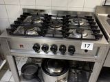 une cuisinière sur laquelle sont posées des casseroles et des poêles, dans une cuisine