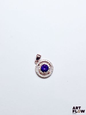 un gros plan d'un pendentif en forme de diamant violet et blanc posé sur une surface blanche