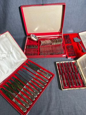 un coffret rouge contenant de l'argenterie, posé sur une nappe bleue