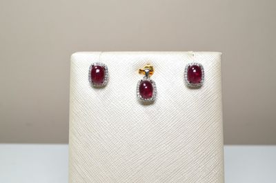 une paire de boucles d'oreilles en rubis et diamants exposée dans une vitrine blanche