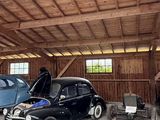 deux vieilles voitures garées dans un garage, avec un homme debout à côté d'elles