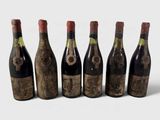 six bouteilles de vin alignées sur une surface blanche