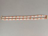 un gros plan d'un bracelet en perles posé sur une surface grise