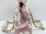 pink and white floral purse with gold chain strap on white surface