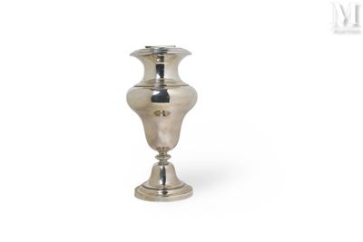 un vase en argent posé sur une surface blanche