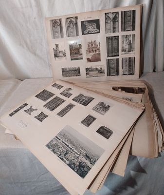 une pile de vieilles photos posée sur un lit, avec une feuille de papier à côté