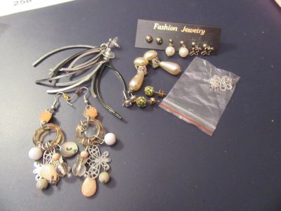 several pairs of earrings sitting on top of a table next to a card
