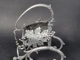 an antique silver plated basket with grapes and leaves on it