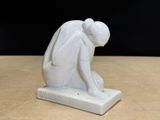 a white figurine of a man kneeling down on a table