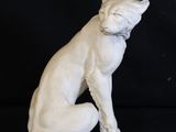 statue d'un chat assis sur ses pattes arrière sur un fond noir