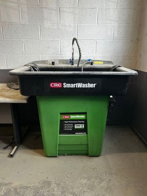 a green trash can next to a sink in a room