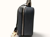 the small black bag has a gold chain hanging from it ' s side