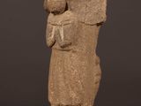 une statue en pierre représentant une femme tenant un enfant dans ses bras, posée sur un socle en bois