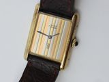 a close up of a watch on a white surface with a brown strap