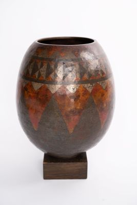a vase that is sitting on a stand on a white surface