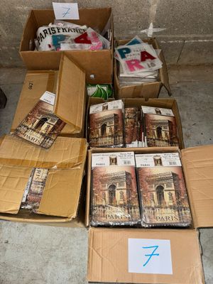 Plusieurs cartons remplis de livres sont posés par terre près d'un mur.