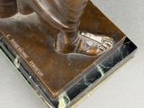 bronze statue of a man with a hat and a robe on a marble base