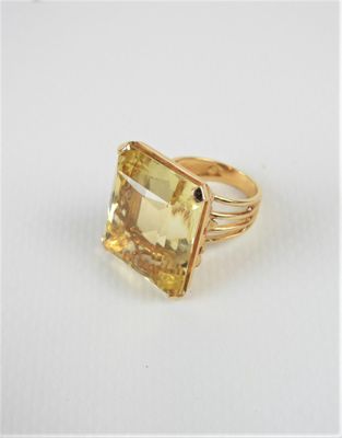 un gros plan d'une bague ornée d'une pierre jaune sur un fond blanc