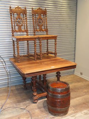 une table en bois avec deux chaises et un tonneau posé par terre