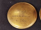 a gold pocket watch that has writing on it