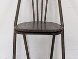a wooden chair that is leaning against a white wall