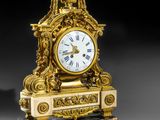 a gold clock sitting on top of a wooden stand