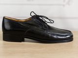 un gros plan sur une paire de chaussures noires posées sur une table en bois
