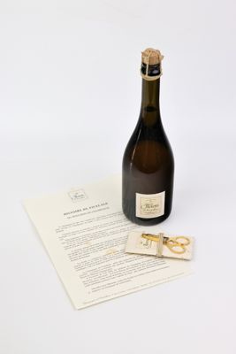 une bouteille de vin posée sur une feuille de papier, à côté d'une paire de ciseaux