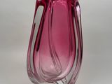 vase en verre violet muni d'une anse incurvée sur un fond blanc