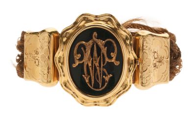 une photo d'un bracelet doré et noir orné d'un monogramme