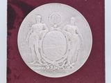 un gros plan d'une médaille d'argent posée sur un socle, sur fond blanc