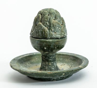 un petit objet vert posé sur une assiette, sur une surface blanche