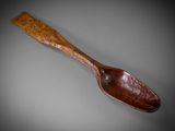 an old wooden spoon with a wooden handle on a gray background