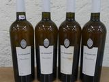 quatre bouteilles de vin sont alignées sur une table en bois
