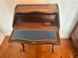 a small wooden desk with a blue top on a hard wood floor