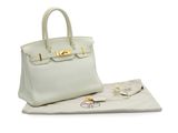 a white leather handbag sitting on top of a white cloth