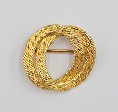 a close up of a gold brooch with a circular design