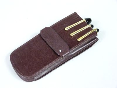 un étui en cuir marron contenant quatre stylos