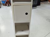 une grande armoire blanche à deux étagères, au milieu de la pièce