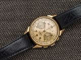 un gros plan d'une montre en or avec un bracelet en cuir noir