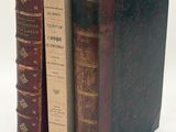 two old books sitting on top of each other on a white surface