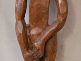 statue représentant un homme tenant un bébé dans ses bras, posée sur un socle en bois