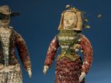 two figurines of a man and a woman wearing hats and gowns
