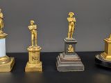 quatre statues d'hommes debout sur des socles posés sur une table