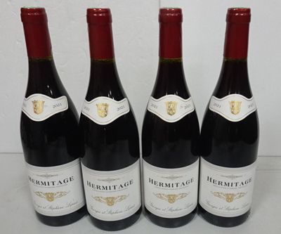 four bottles of red wine are lined up on a table
