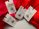three tags are attached to a red jacket on a white surface