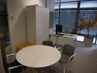une table et des chaises blanches dans une pièce dotée d'une grande fenêtre