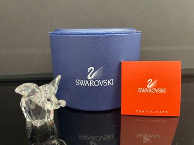 une figurine d'éléphant en verre à côté d'une boîte de Swarovski