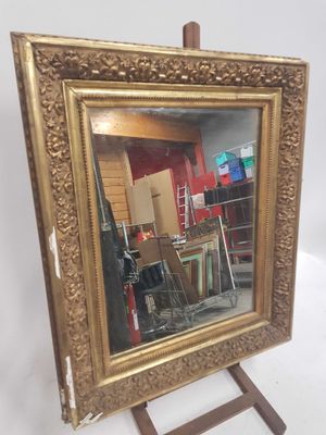 une image représentant un miroir à cadre doré posé sur un chevalet en bois