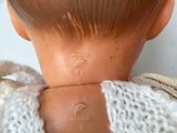 a close up of a doll ' s head with a sweater on